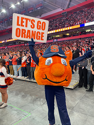 Otto the Orange in the Dome holding a "Let's Go Orange" sign.