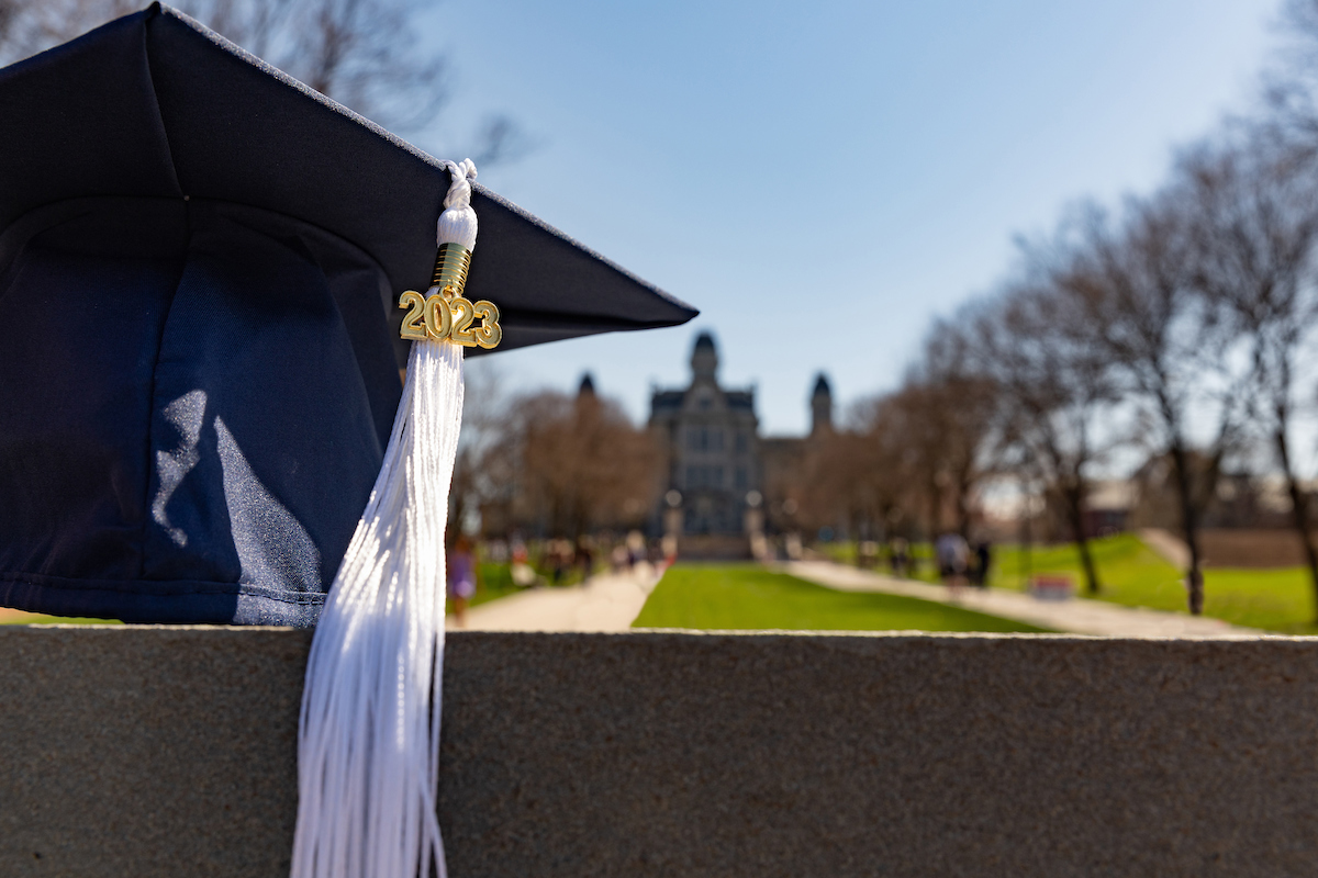 a close-up of a 2023 tassel and mortarboard against the backdrop of the Hall of Languages