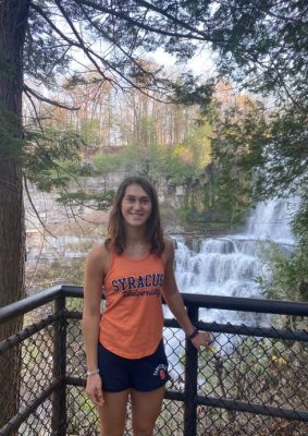 Taylor Fein poses in a Syracuse shirt near a waterfall