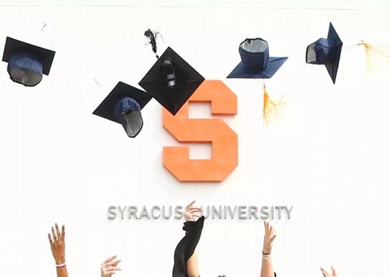 graduation caps being thrown in the air in front of a building with the block S and words Syracuse University