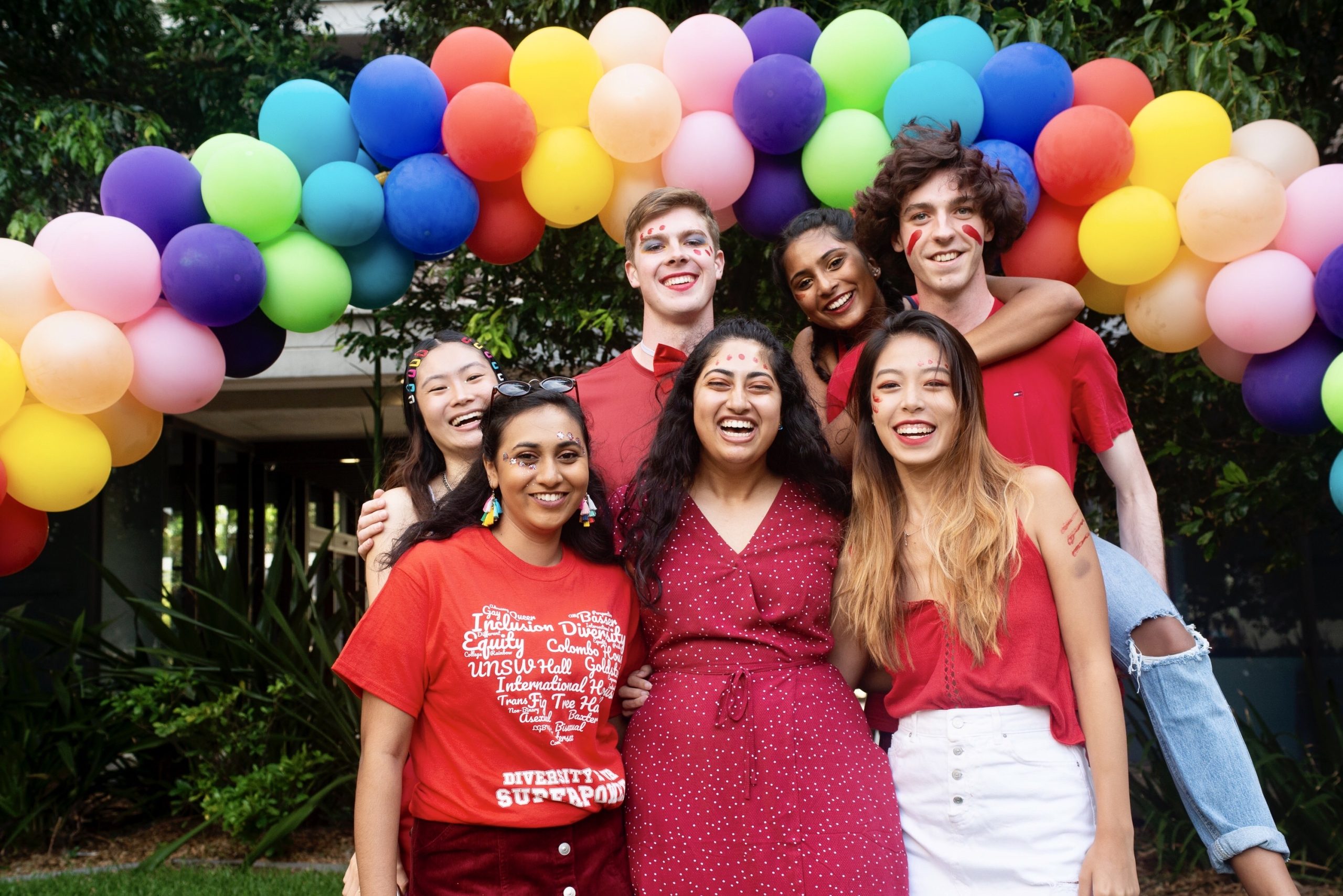 group of people in front of set of balloons in rainbow colors