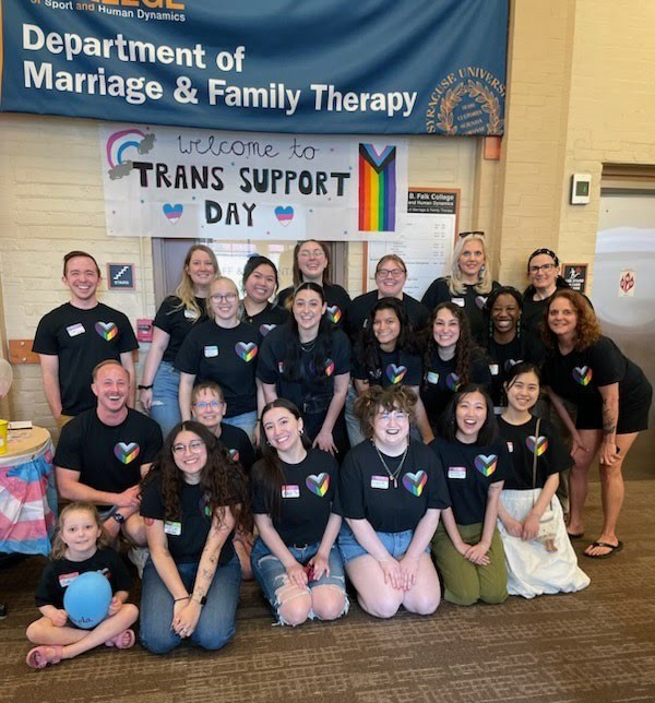 Members of the University's Trans and Gender Expansive Support Team pose together amidst tables of clothing at the Trans Support Day event in April