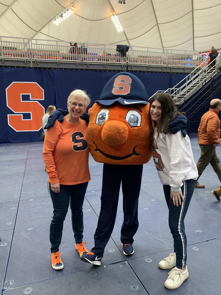 Two individual posing with Otto at a basketball game. 