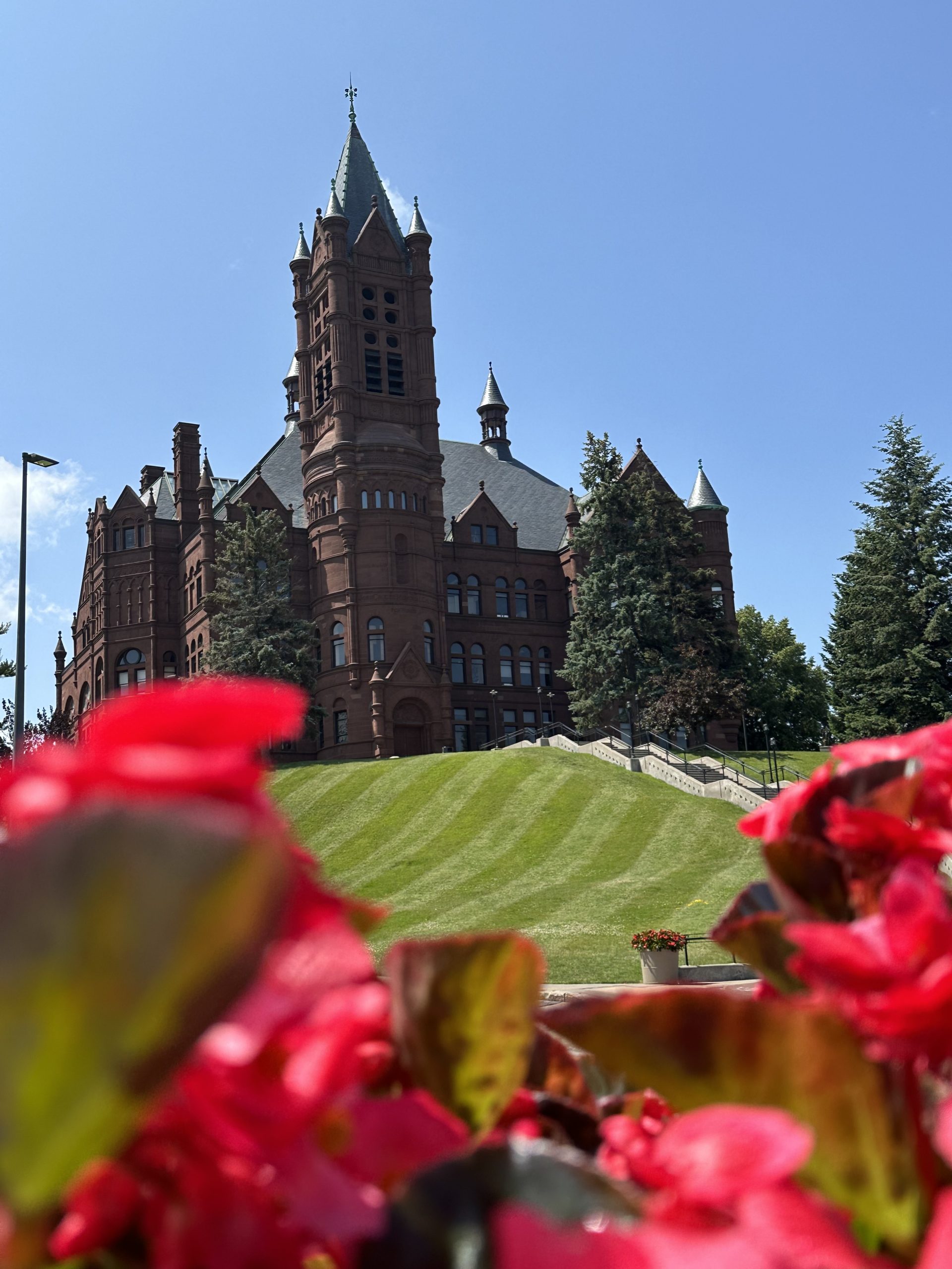 Crouse College in the background with red flowers in the foreground.