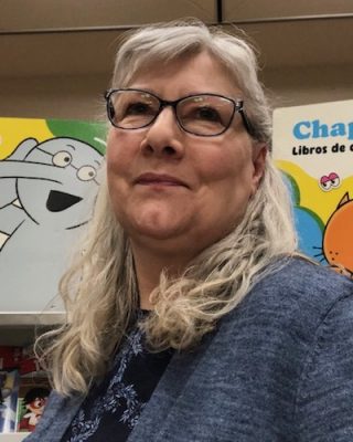 Janet Schuster portrait in front of children's books