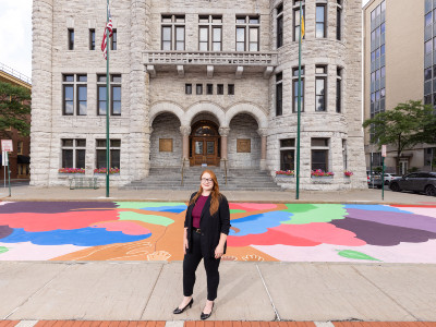 Jessica Whitley stands in front of the mural she designed at Syracuse City Hall 