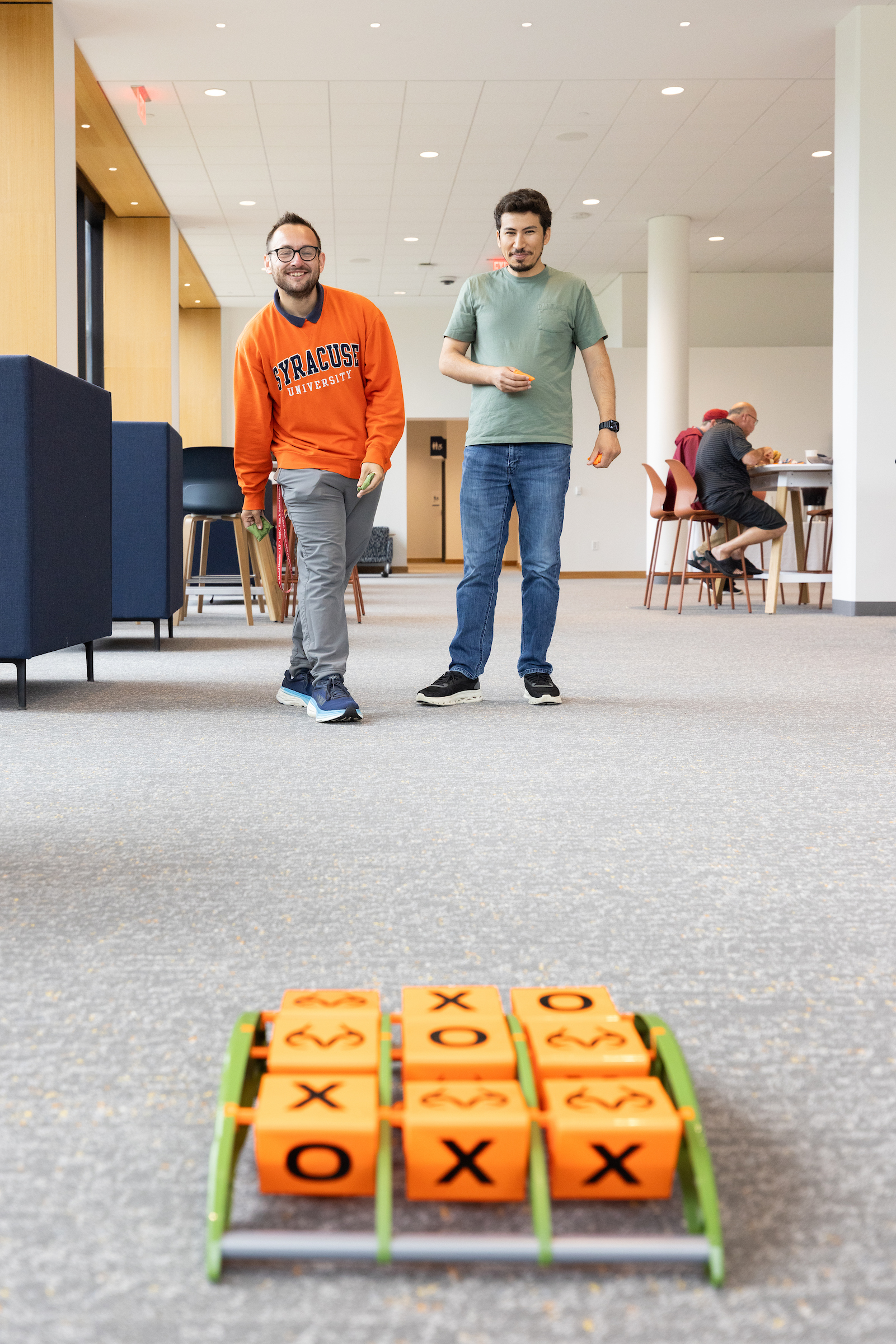 Two individuals play a bean bag toss version of tic tac toe. 