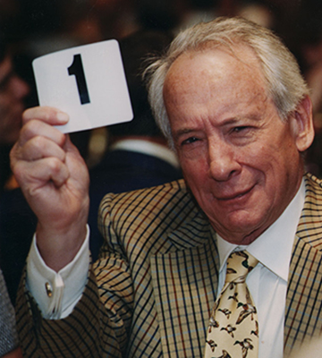 Gerald Cramer holding up a white card with a black number 1 on it