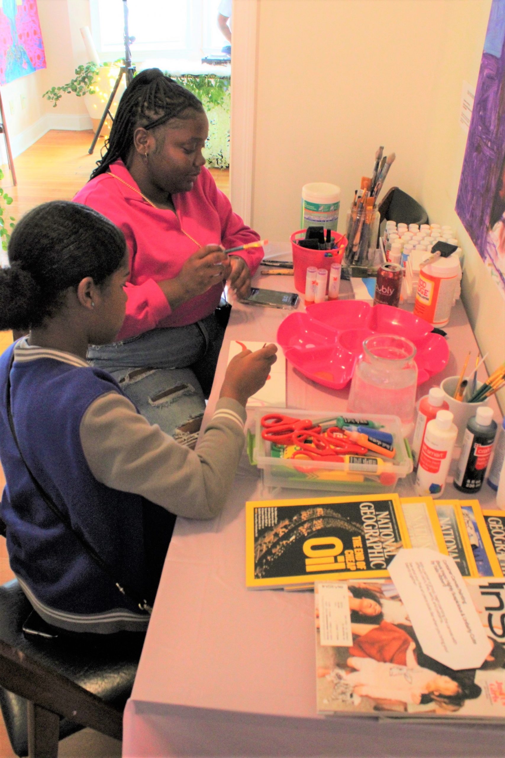 a woman and a girl doing art work with supplies at a desk