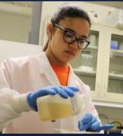 young woman pouring liquid from a jar in a science lab