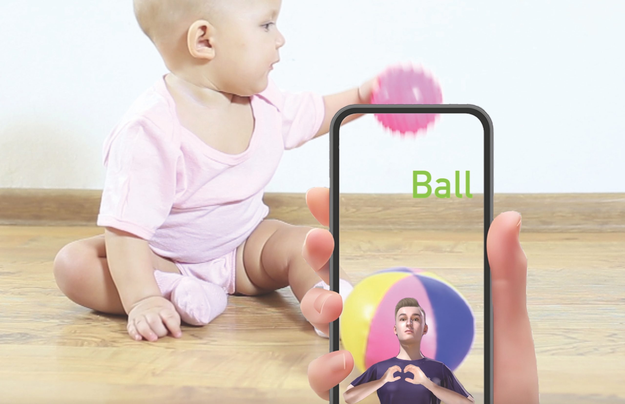 A baby plays with a ball while a hand holds a phone in the foreground