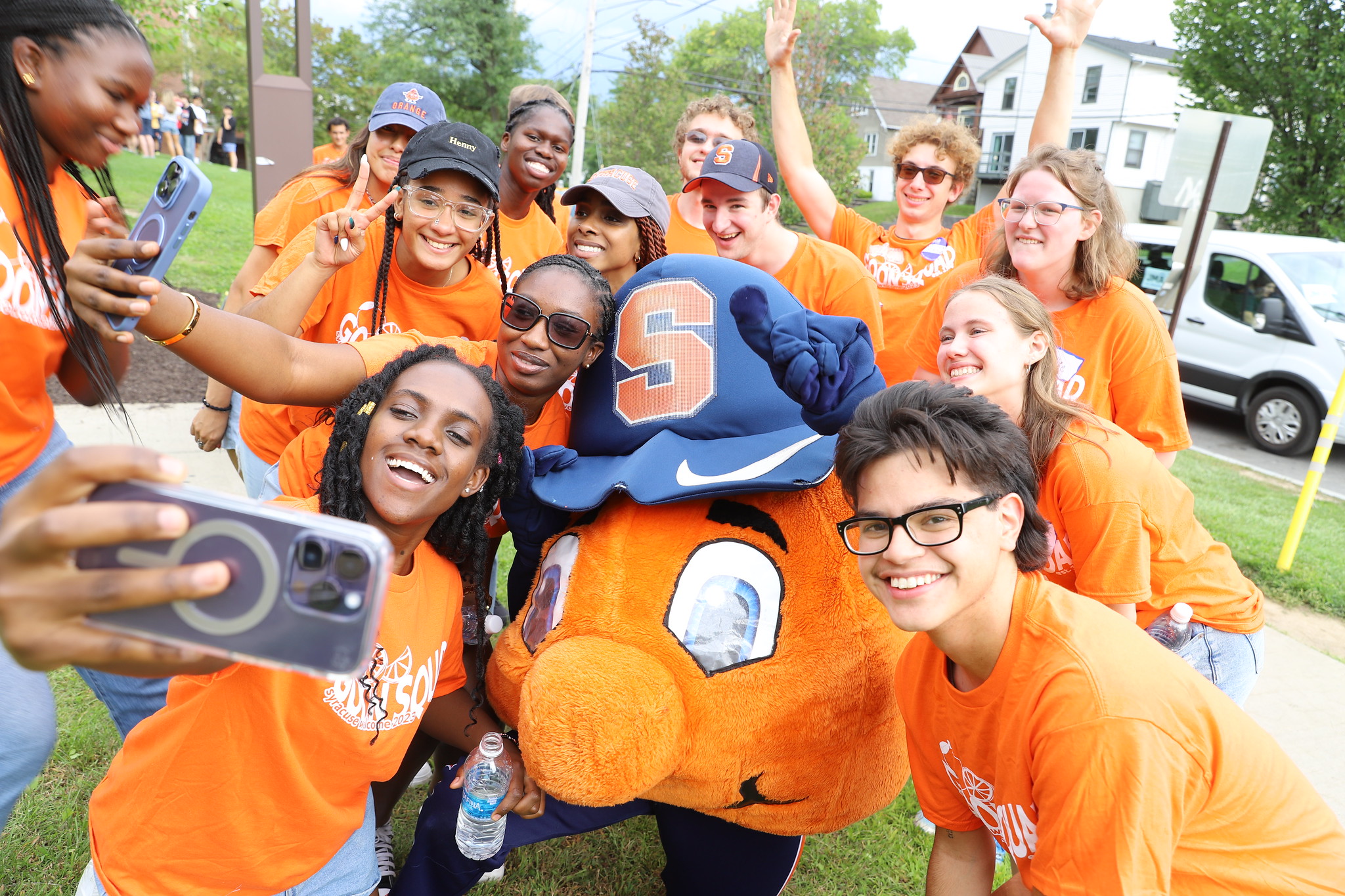 Students in orange shirts gather around Otto the Orange to take a photo