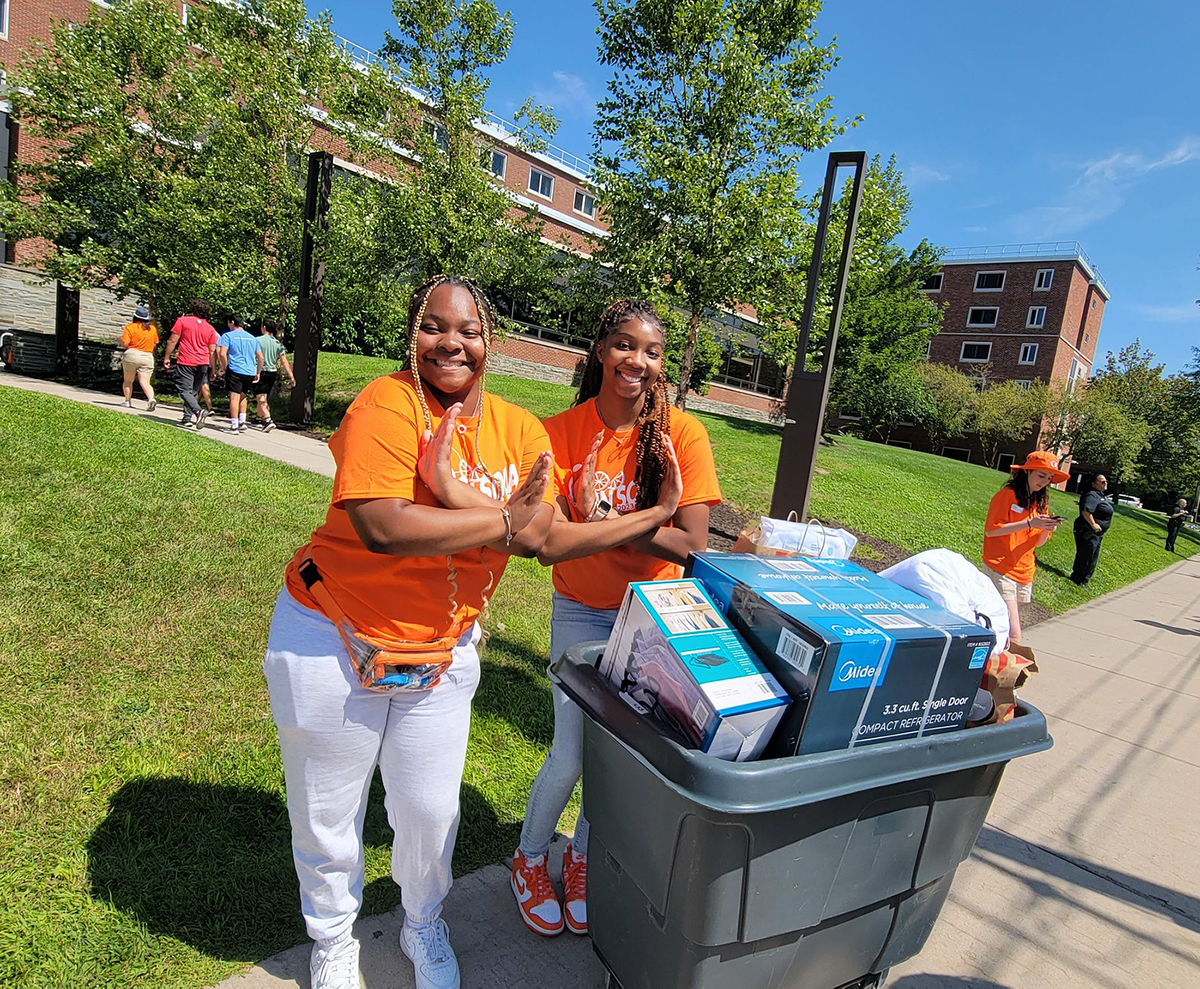 Two Goon Squad members pose together next to a move-in bin
