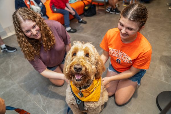 Two students petting a therapy dog.