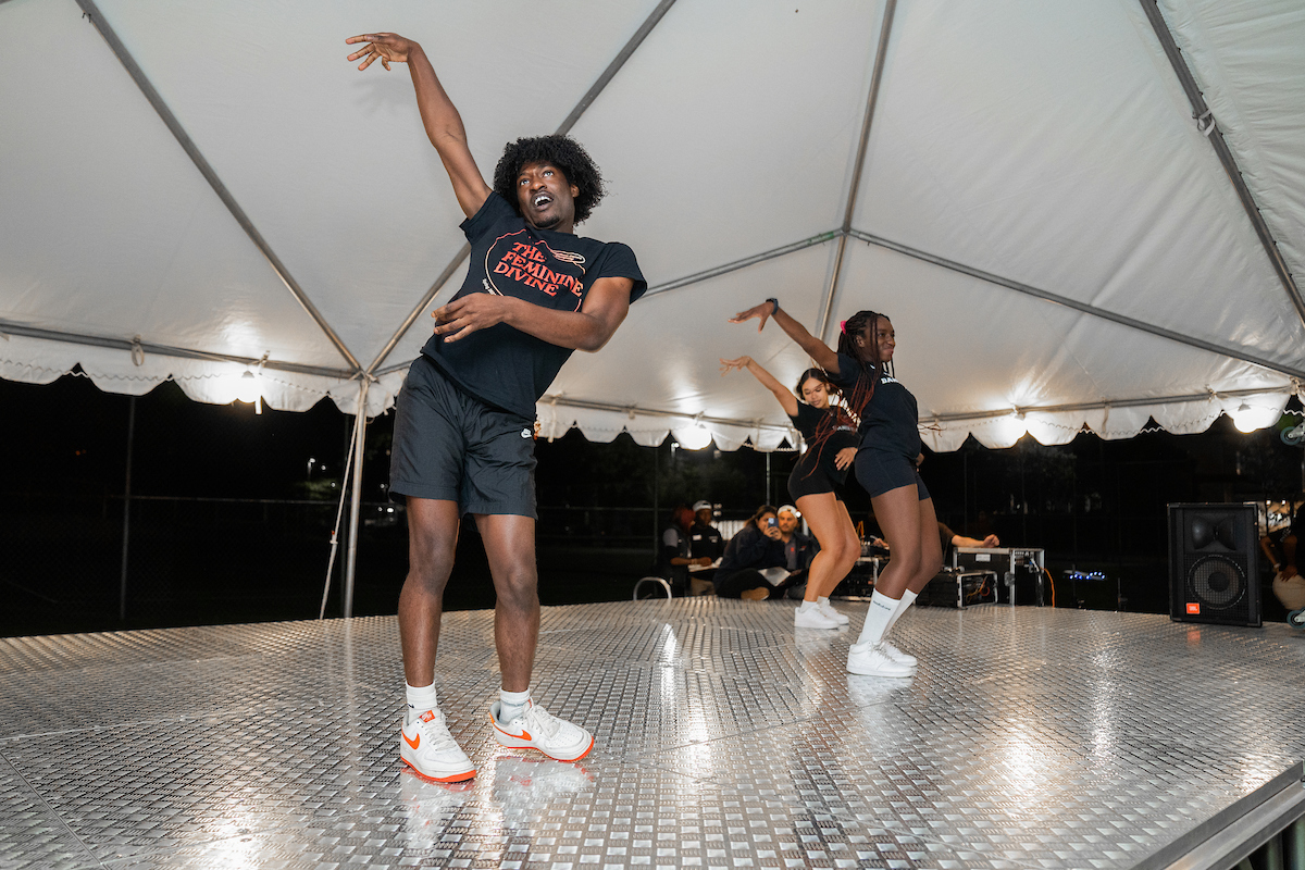 Students perform a dance routine under a tent at the Syracuse Welcome Fête 