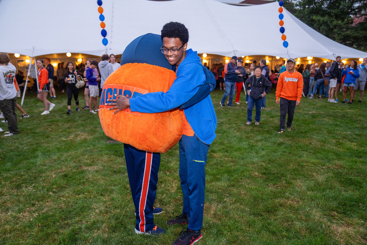 A student hugs Otto outside of a tent on the Quad