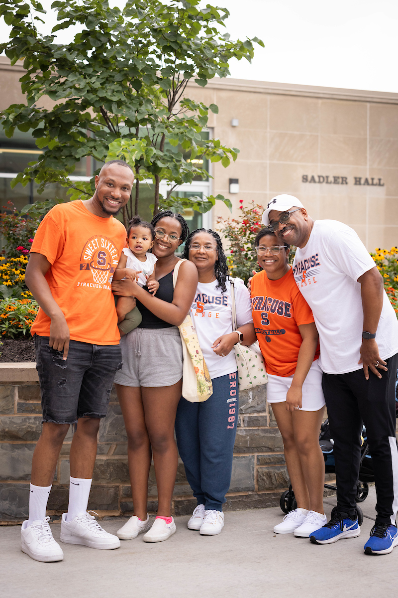 A family of six poses outside of Sadler Hall during move-in