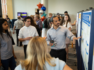 Student giving poster presentation with others listening