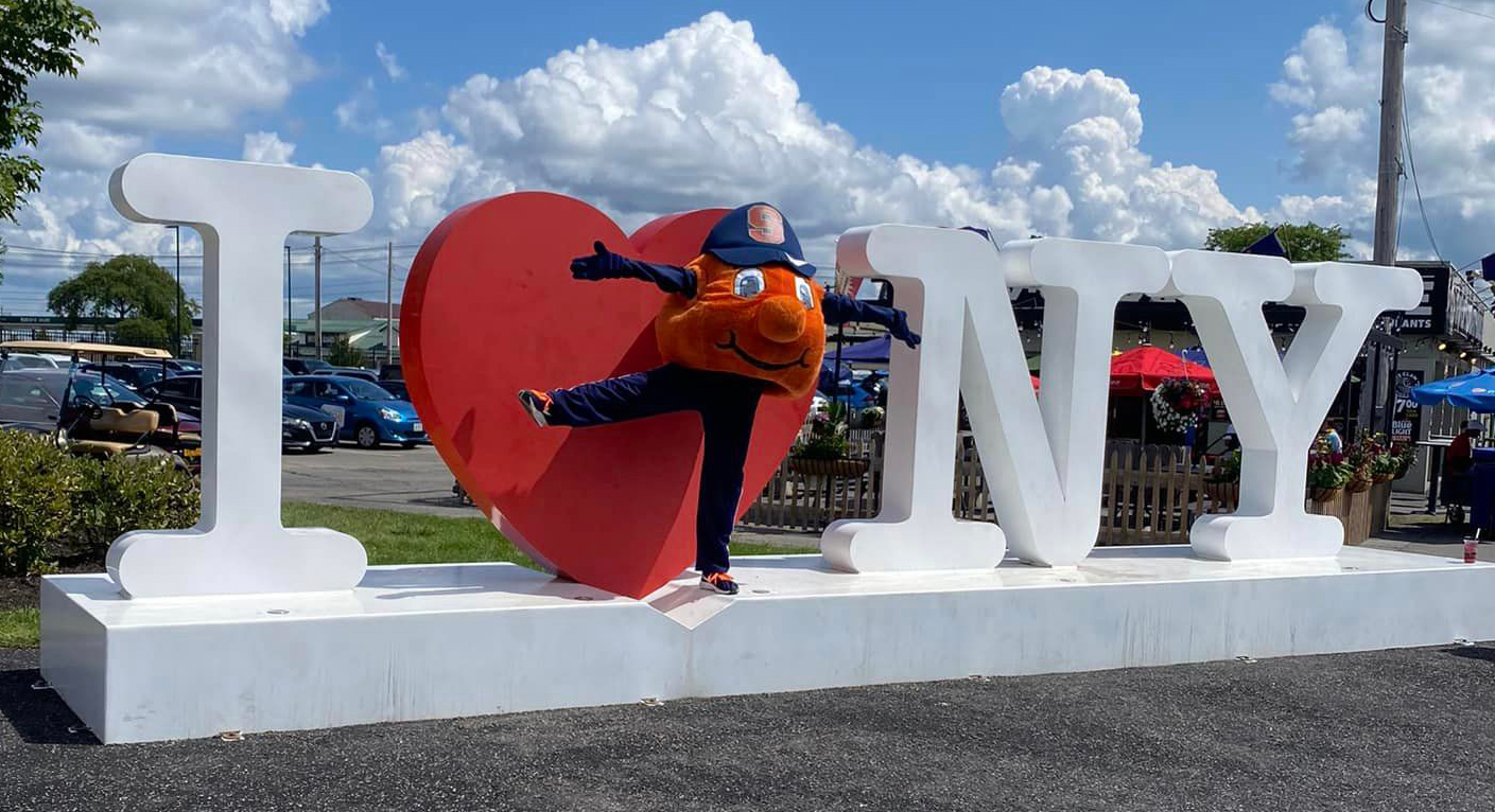 Otto the Orange in front of the I love NY sign at the NY state fair