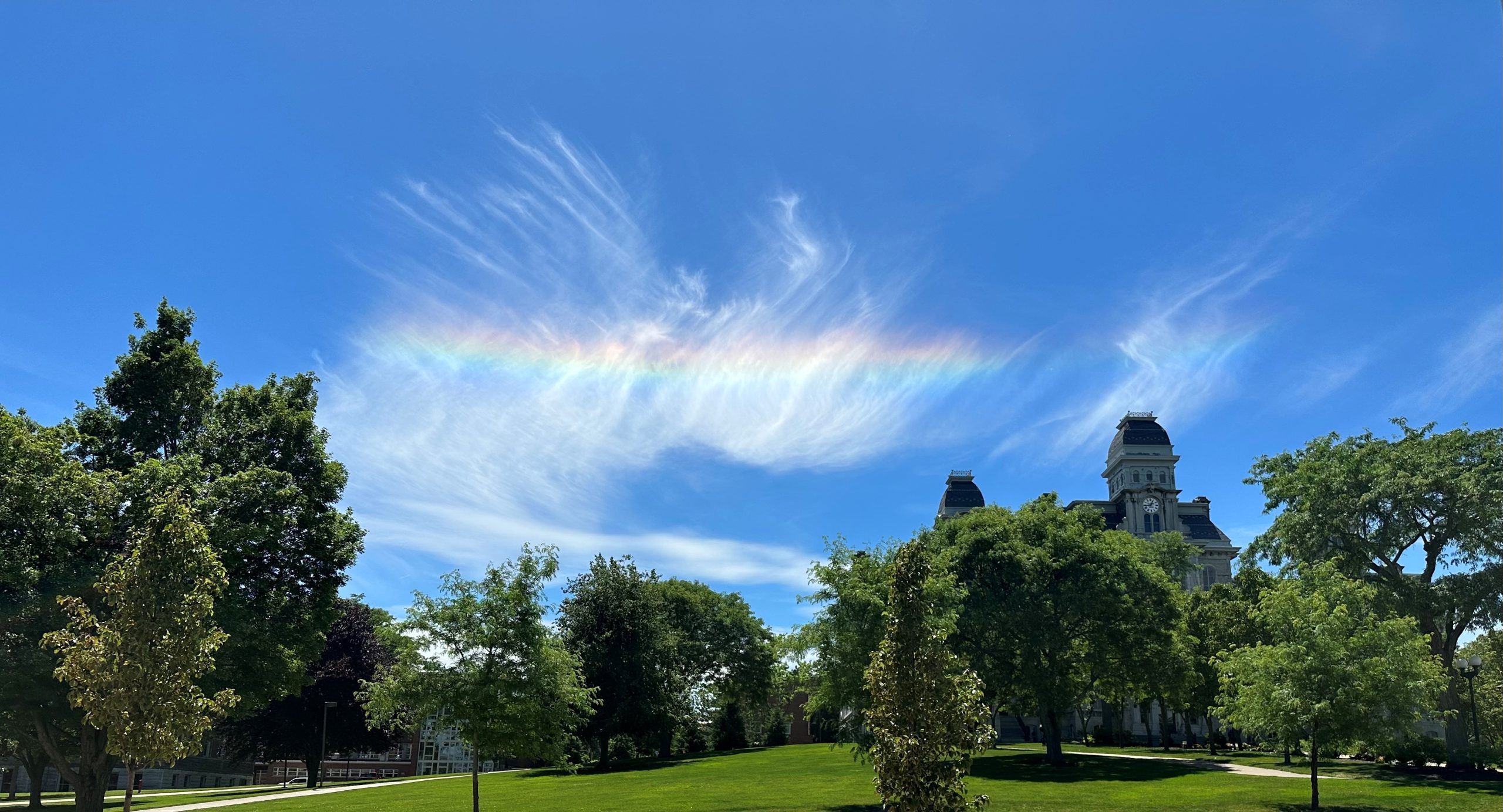 Rainbow clouds in a blue sky over campus.