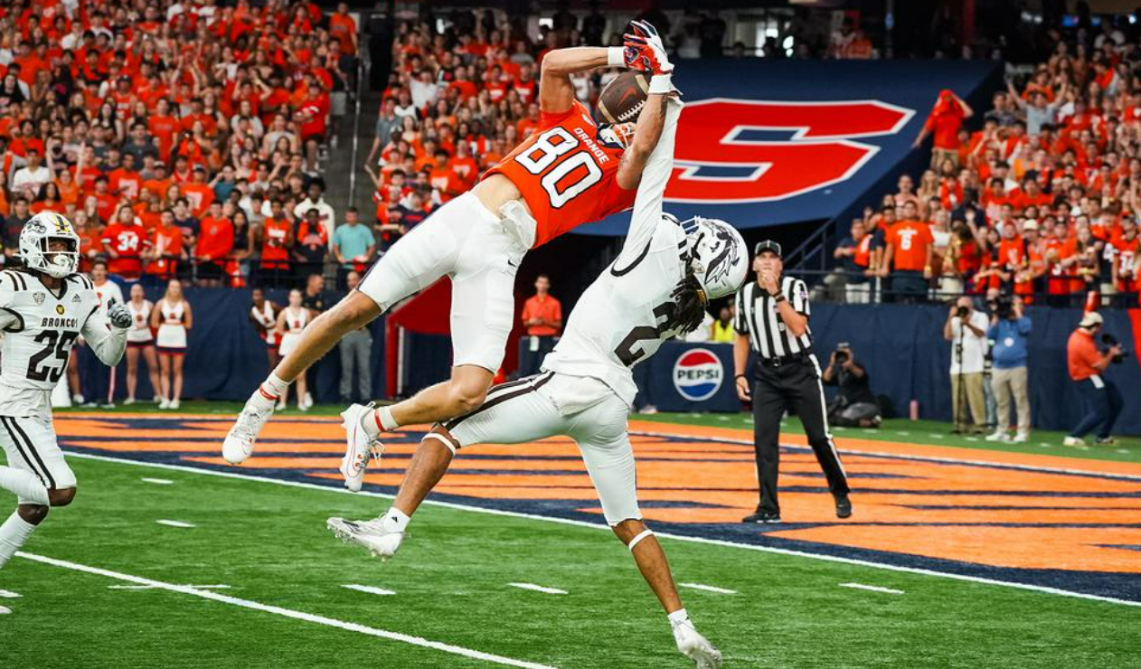 A Syracuse University football player comes down with a catch in the team's win over Western Michigan. Fans cheer in the background.
