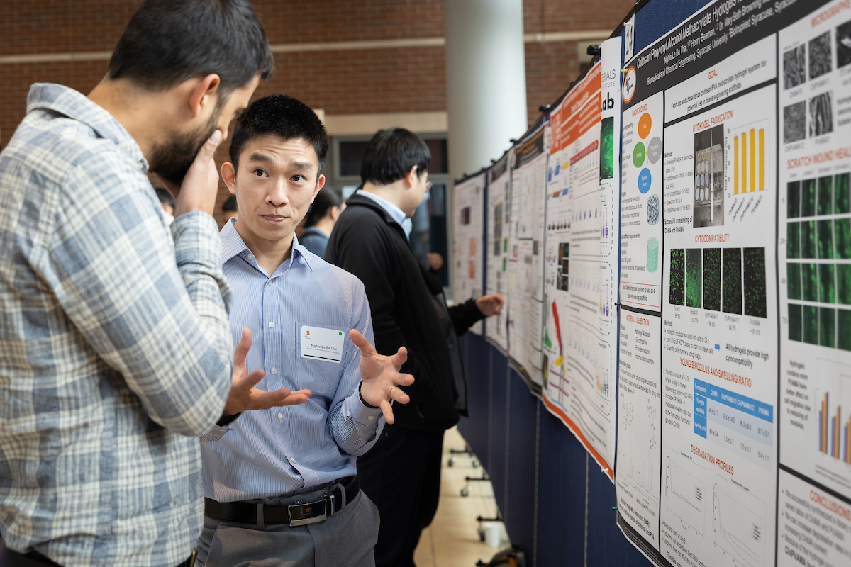 Two students converse next to a research poster at least year's BioInspired Symposium