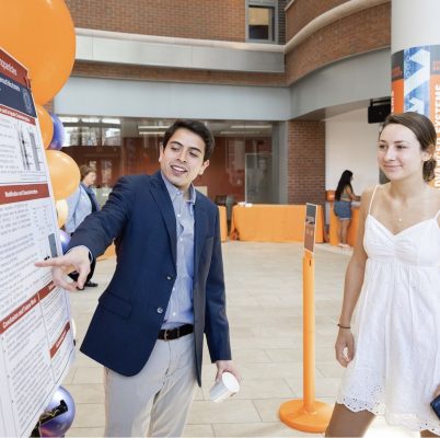 Miguel Guzman presents to another student at a research poster session