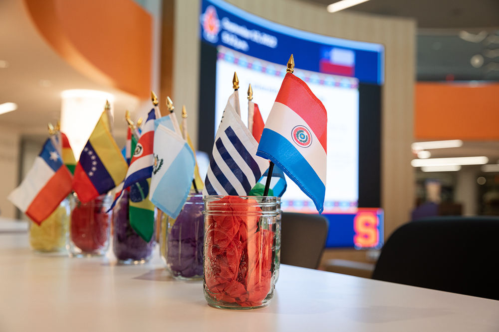 Mason jars filled with colored tissue paper with various small county flags sticking out of them. 