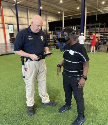 Individual with a virtual reality headset on and an officer standing next to them to assist