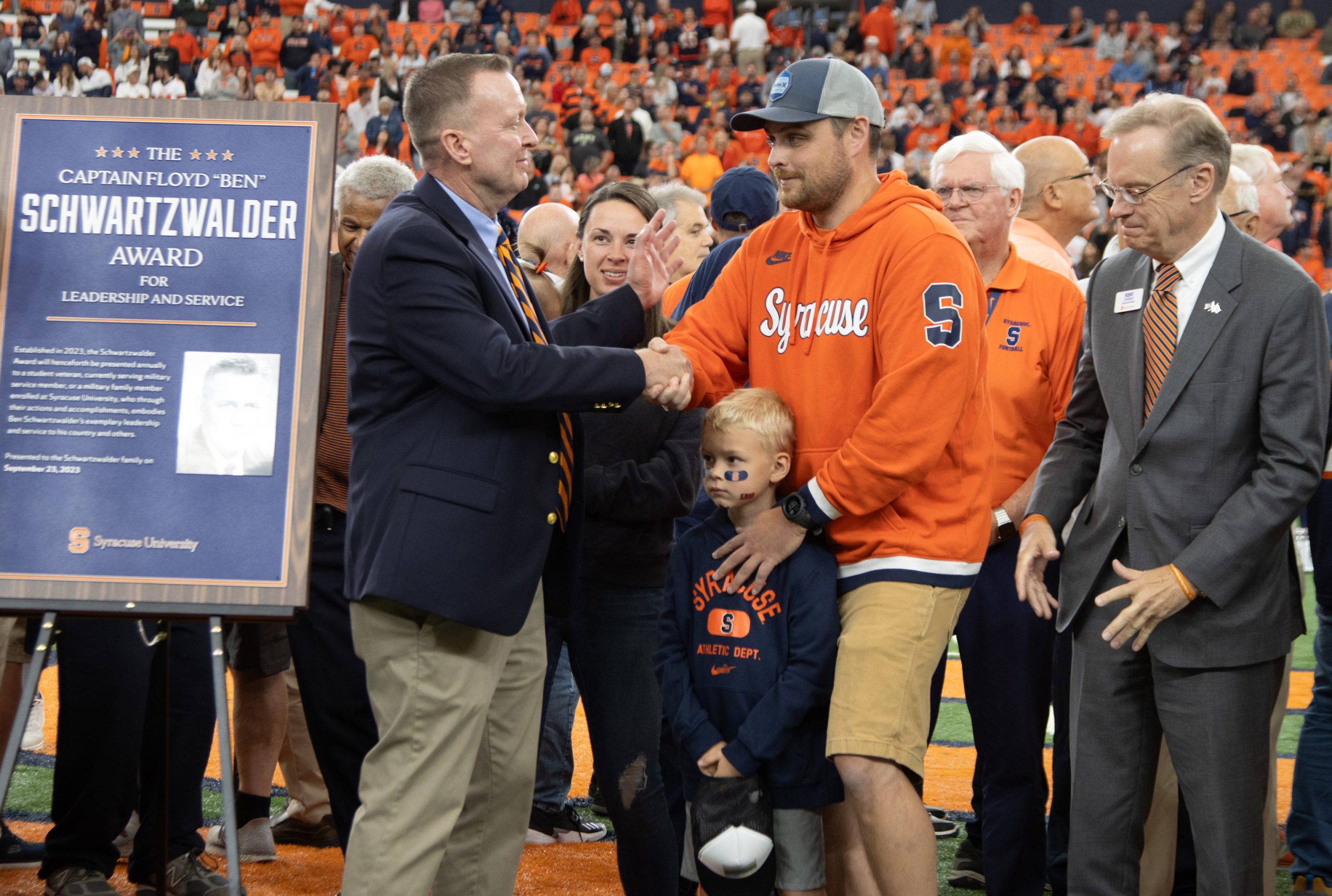 Mike Haynie shaking the hand of a man standing with his boy on the field in the Dome. 