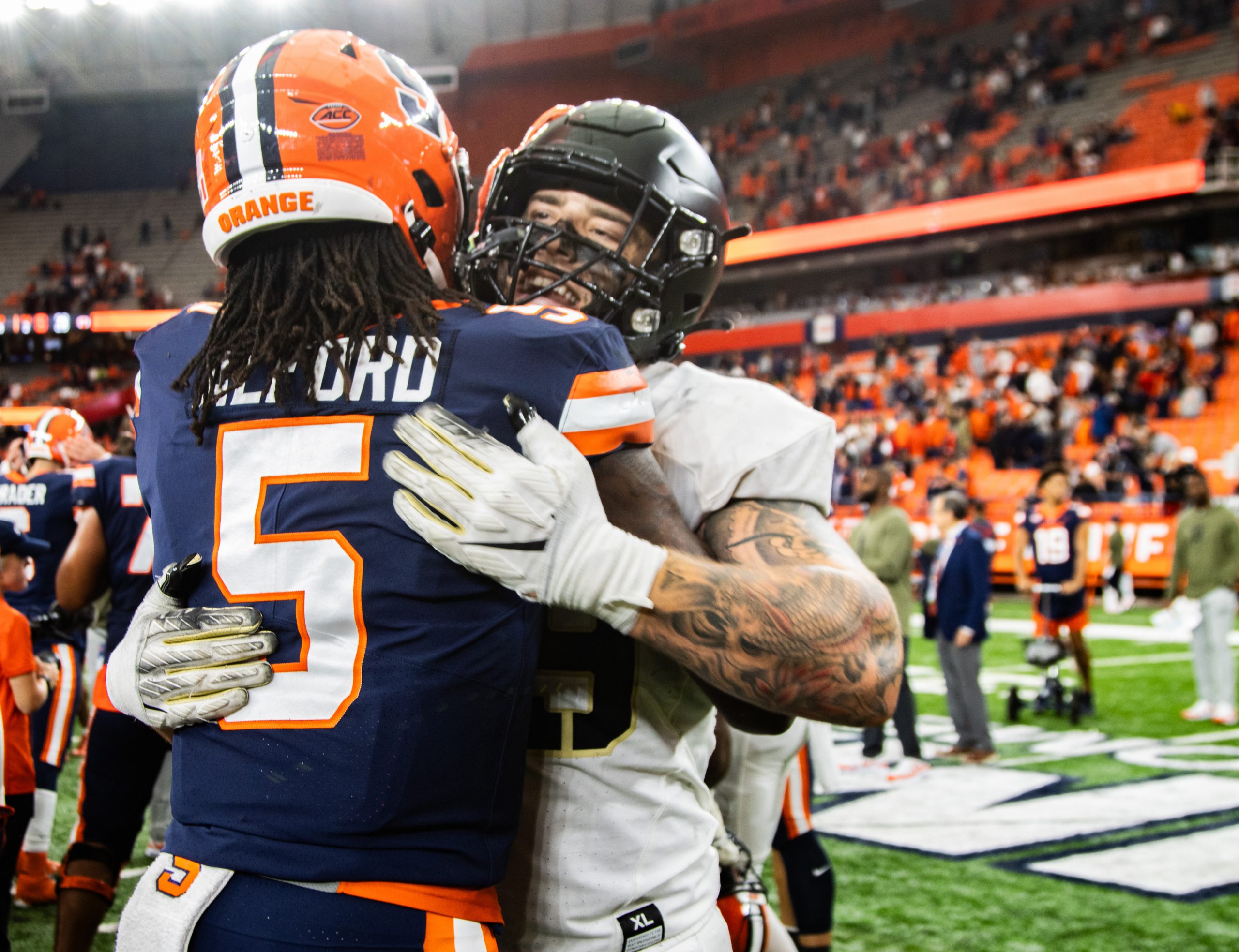 Two football players hugging on the field. 