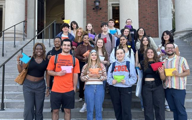 a group of students on the steps pose with hygiene packs they made for donation
