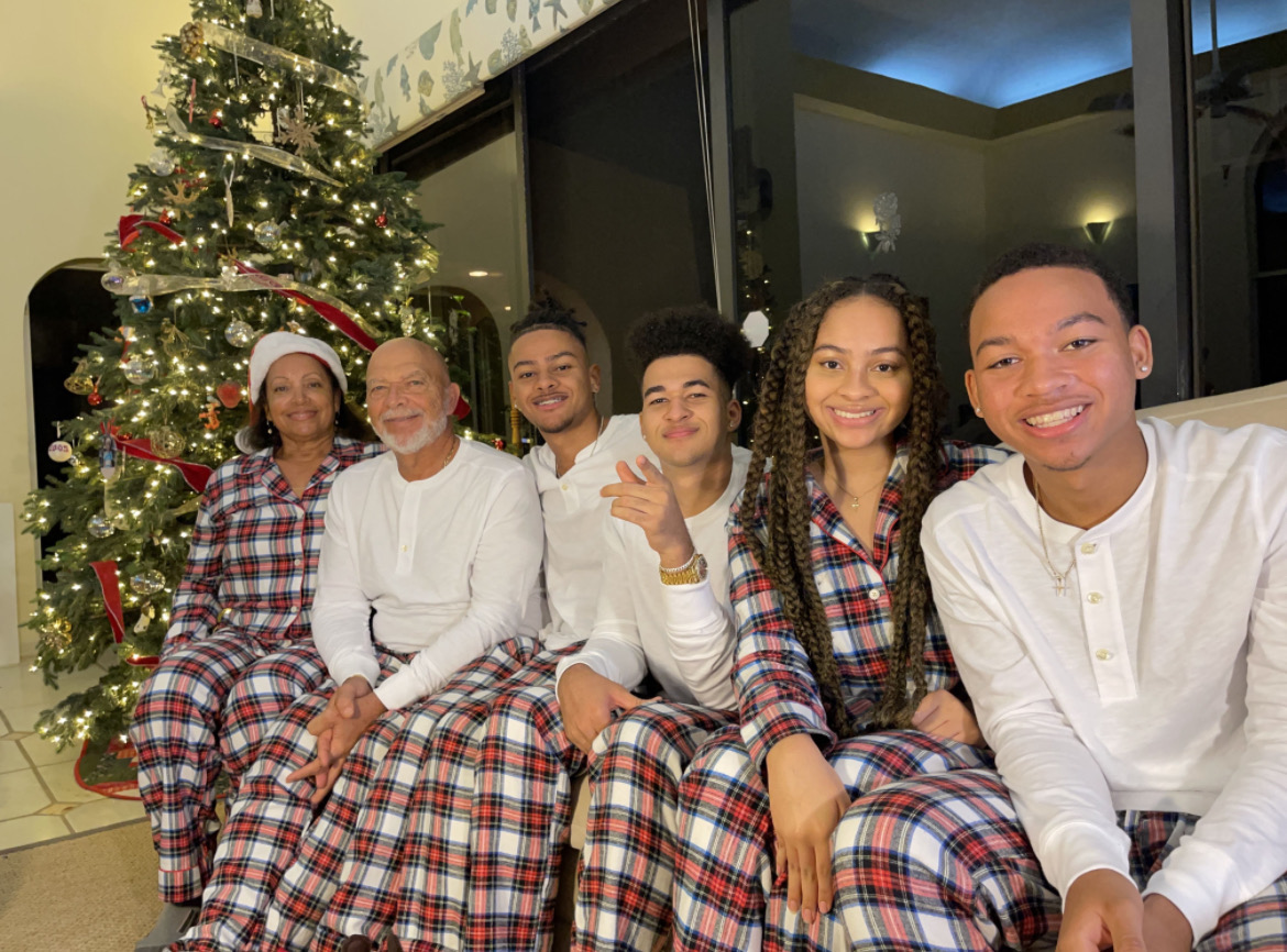 Capdeville family poses together in matching pajamas in front of a Christmas tree during the holidays