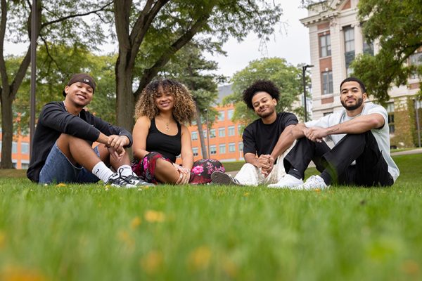 Dougie, Savanna, Donovan and Gabe Capdeville smile while hanging out together on the grass on campus