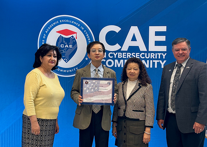 Four people standing together with one of the individuals holding a certificate