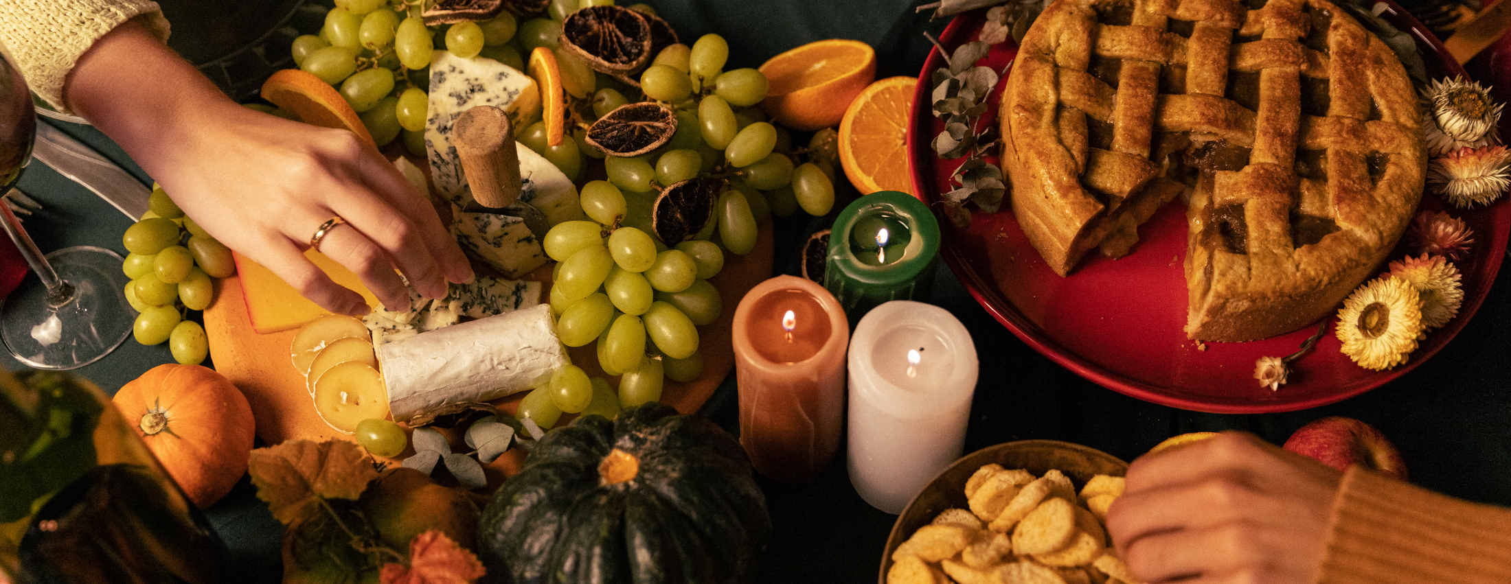 Table filled with grapes, oranges, candles and a pie