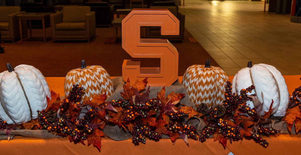 Table scape with different colored pumpkins an orange block S and an orange table cloth.