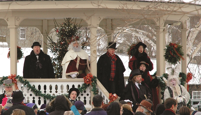 People standing in a gazebo in the winter dressed as Dickens characters