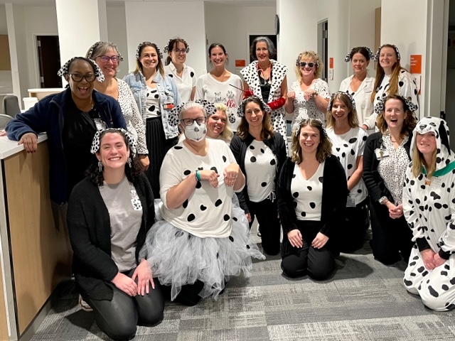 Group of people in an office setting all dressed like Dalmatian dogs.