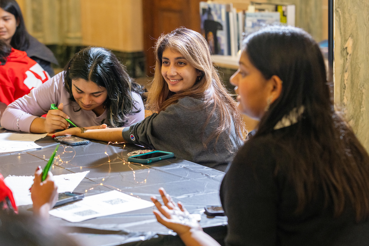 Students sitting at a table doing Henna. 