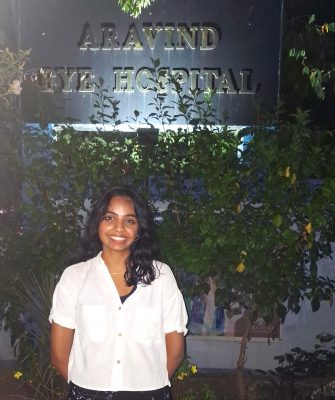 A woman smiles while posing for a photo outside of the Aravind Eye Hospital.