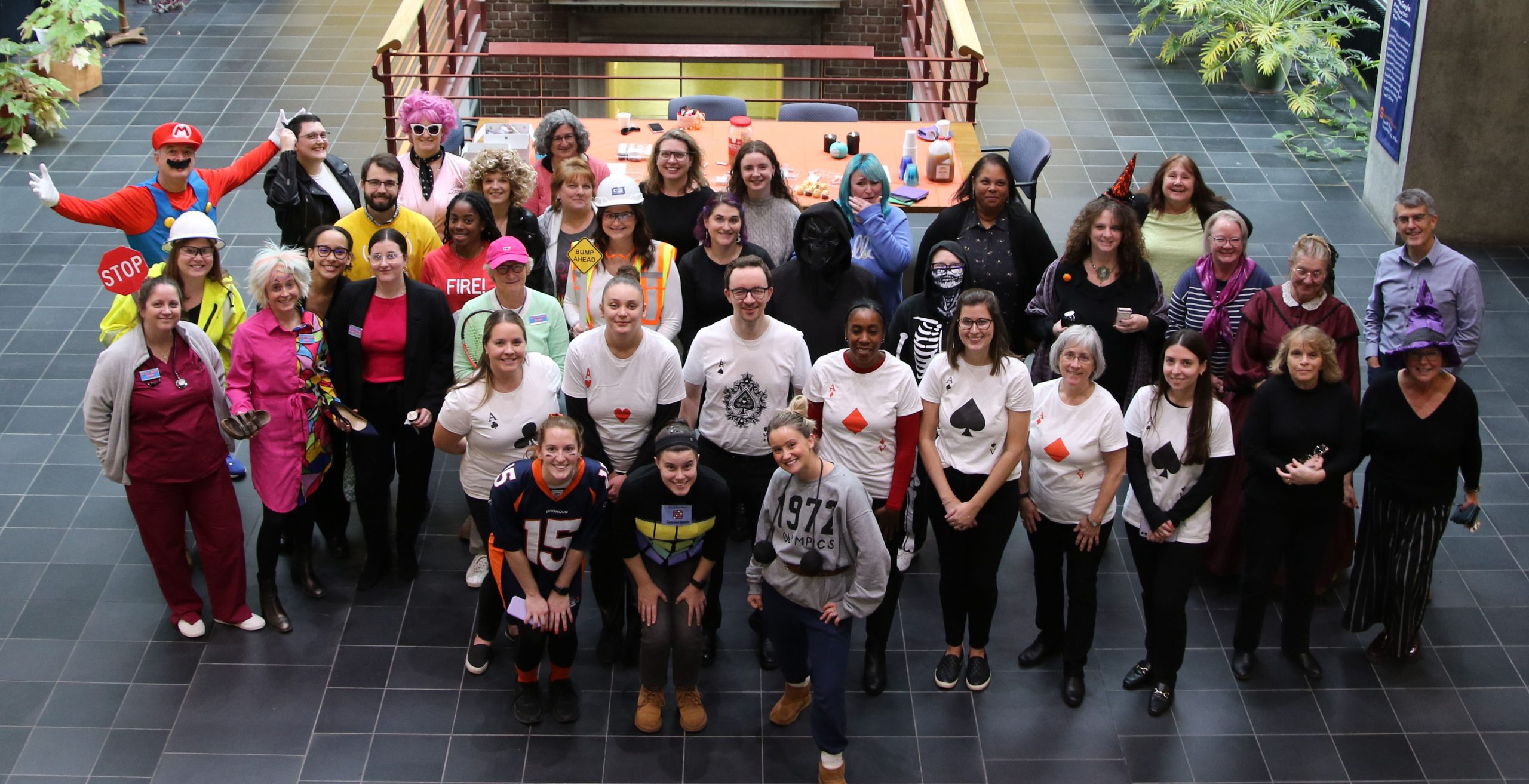 Large group of staff members posing for a picture in various Halloween costumes