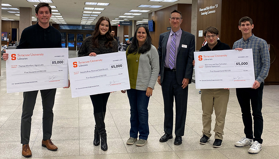 group of individuals standing in Bird Library holding up oversized checks