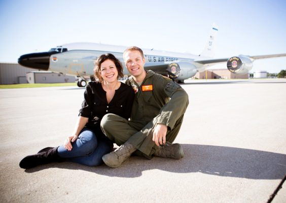 A husband and wife pose in front of a military aircraft.