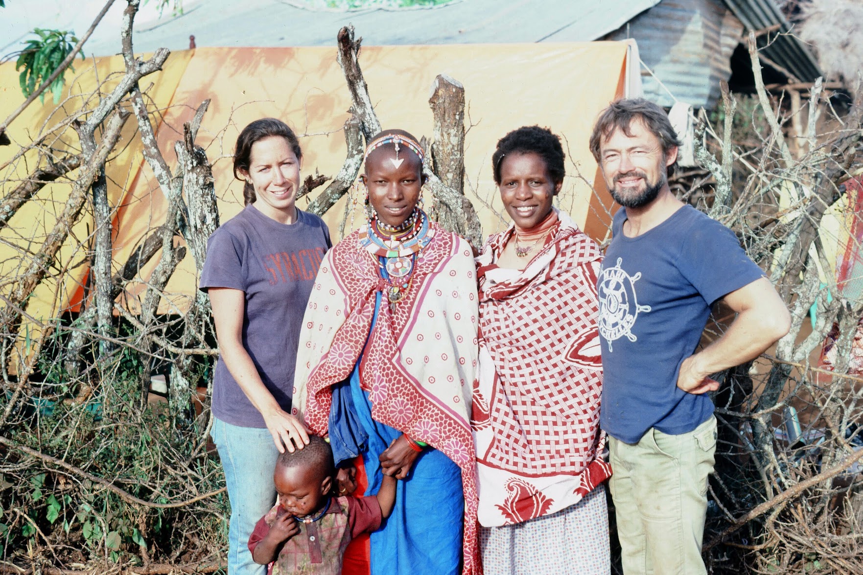 Two Kenyan women and a child stand with Suzanne Grant Lewis and her husband