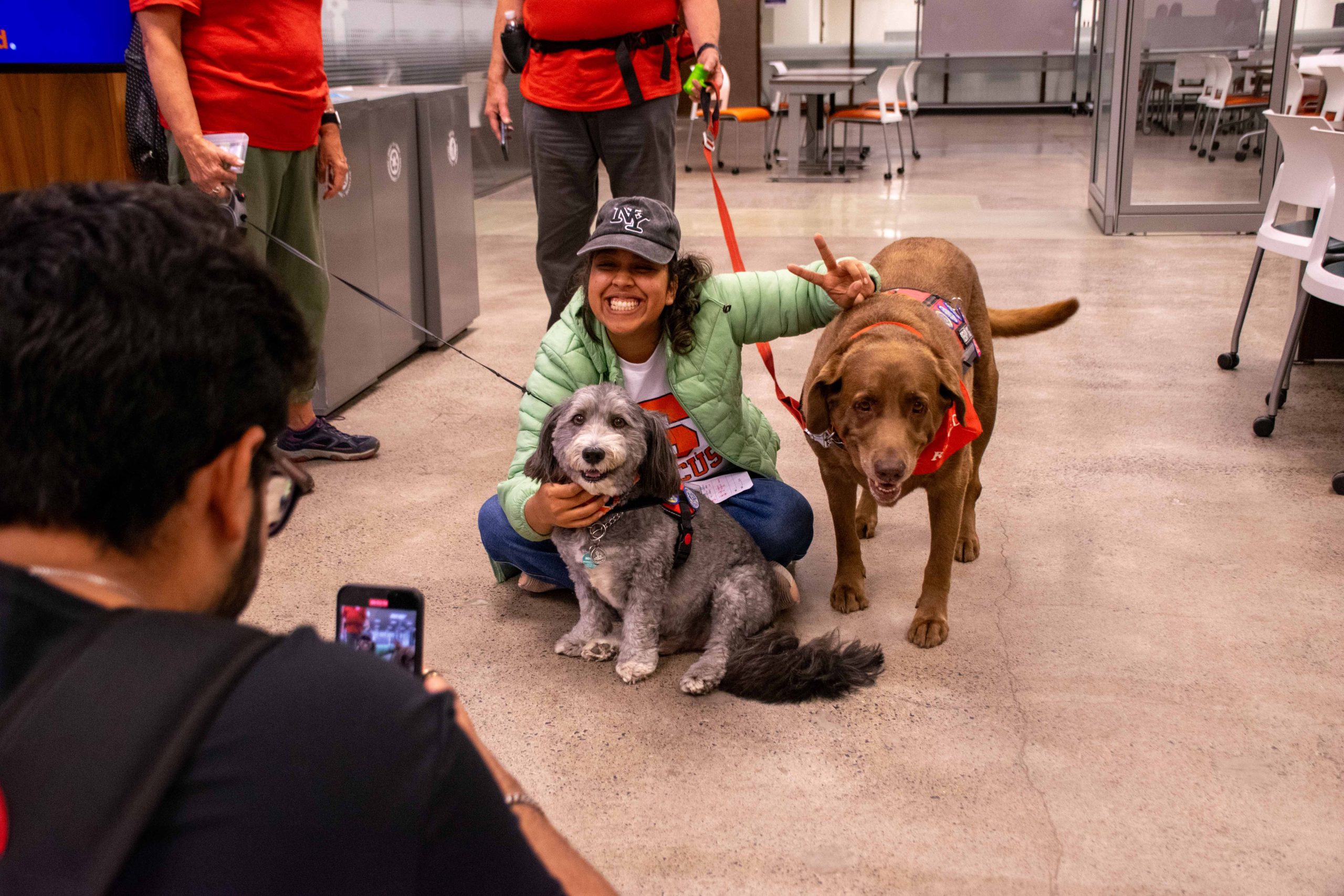 Student posing with two therapy dogs while someone takes their picture. 