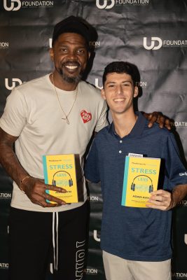 Udonis Haslem and Adam Avin pose together holding copies of the book "Stress Less: Mindfulness for Teenagers"