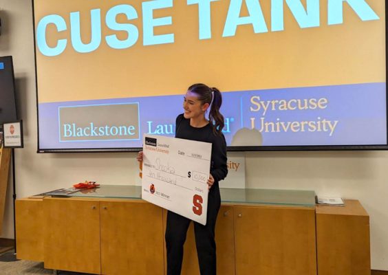 A woman holds up a check for winning during the annual ’Cuse Tank entrepreneurial competition.