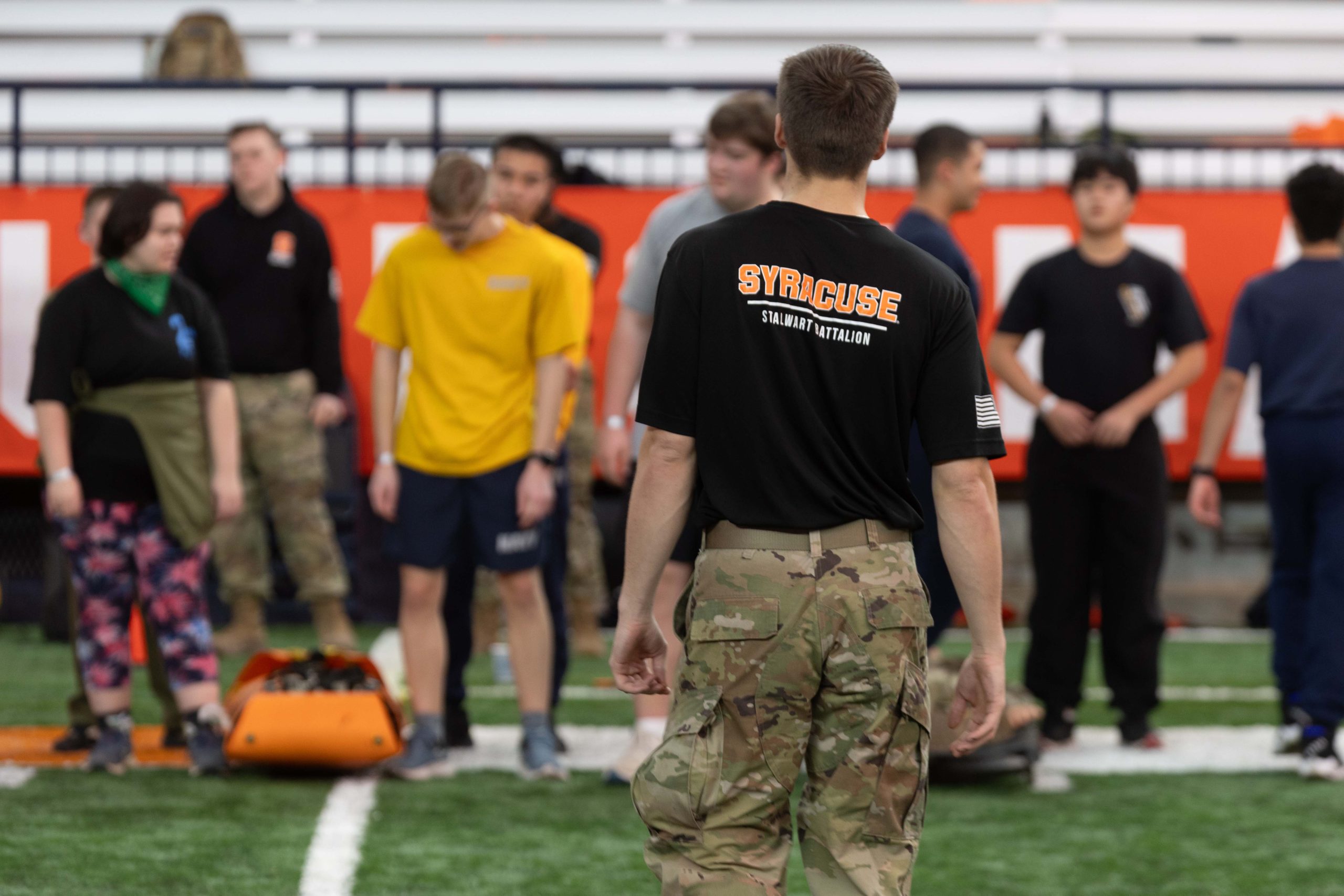 One person standing facing a large group of other people before an exercise on the field in the JMA Dome.