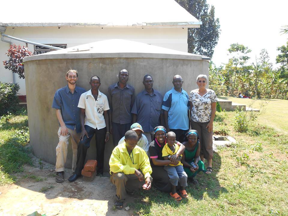 Group of people standing together for a picture in front of a rainwater tank.